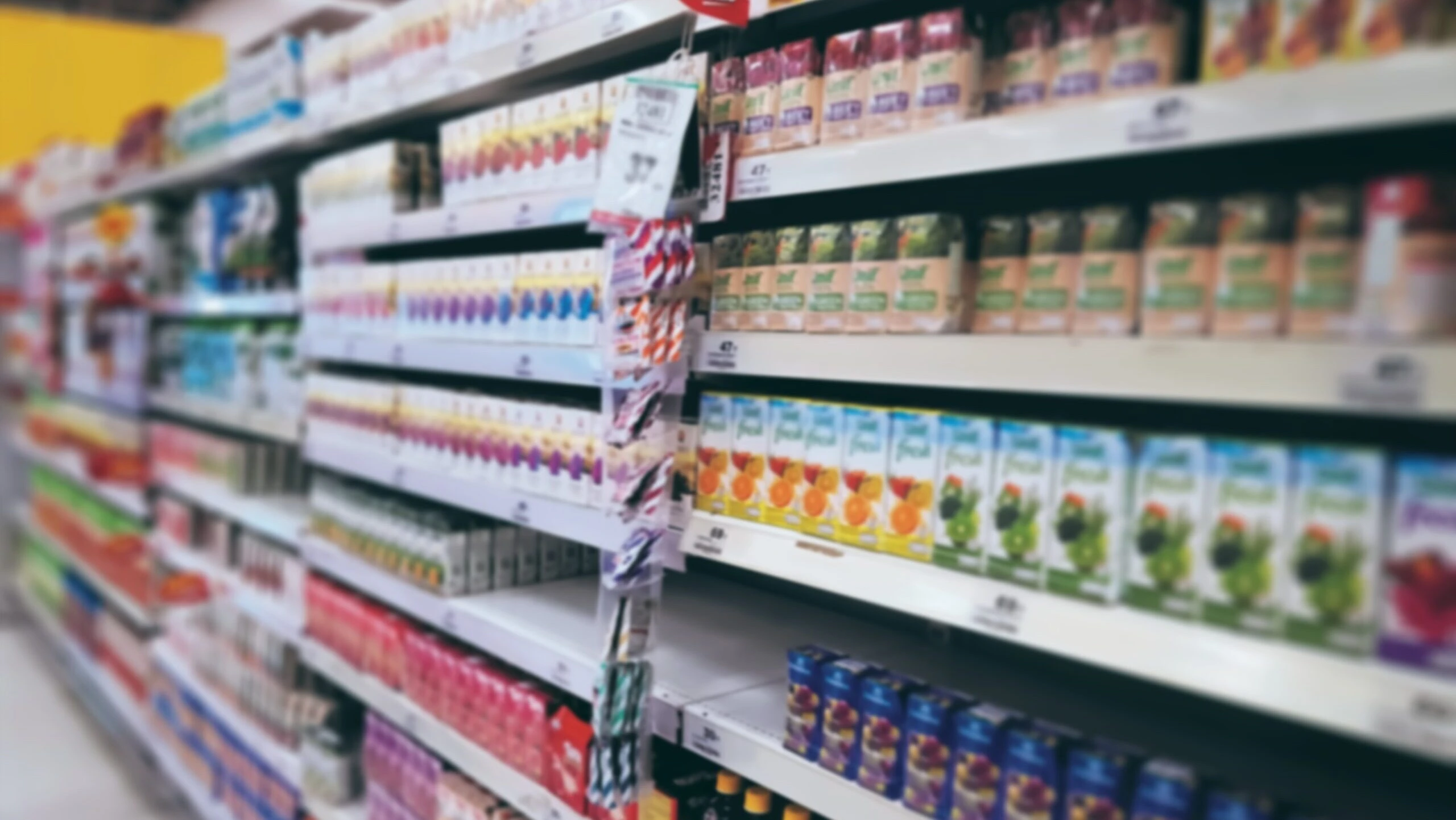 Supermarket shelves stocked with a variety of packaged fruit juices and beverages, arranged in colorful rows in a grocery store aisle.