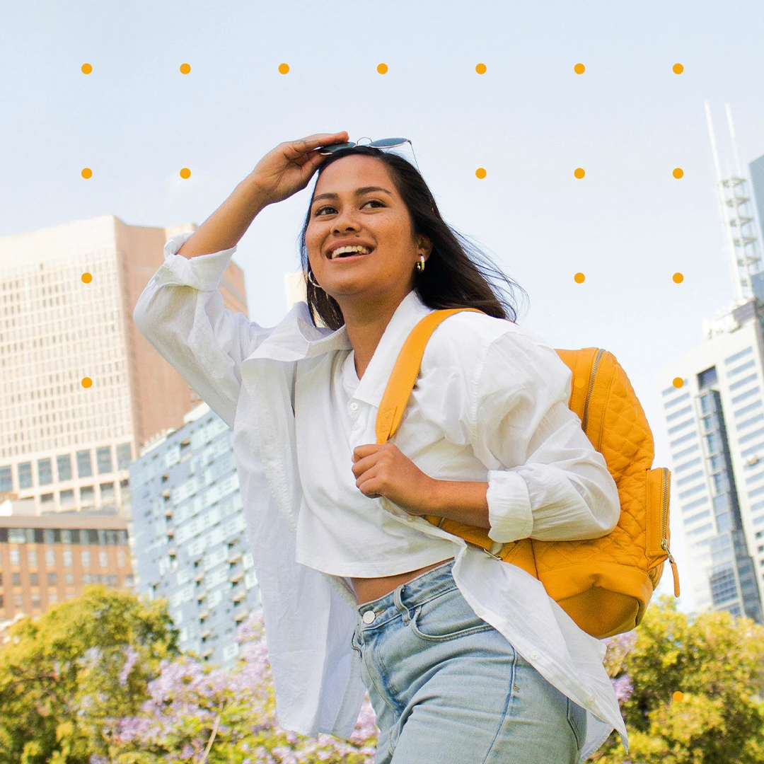 Smiling student with a yellow backpack in a sunny city