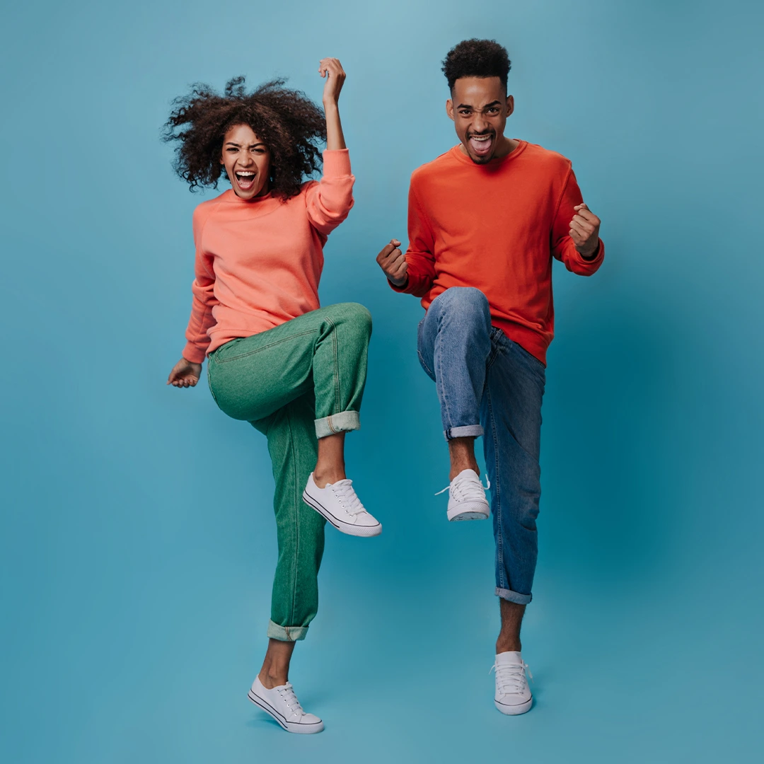 Two people jumping in celebration against a blue background