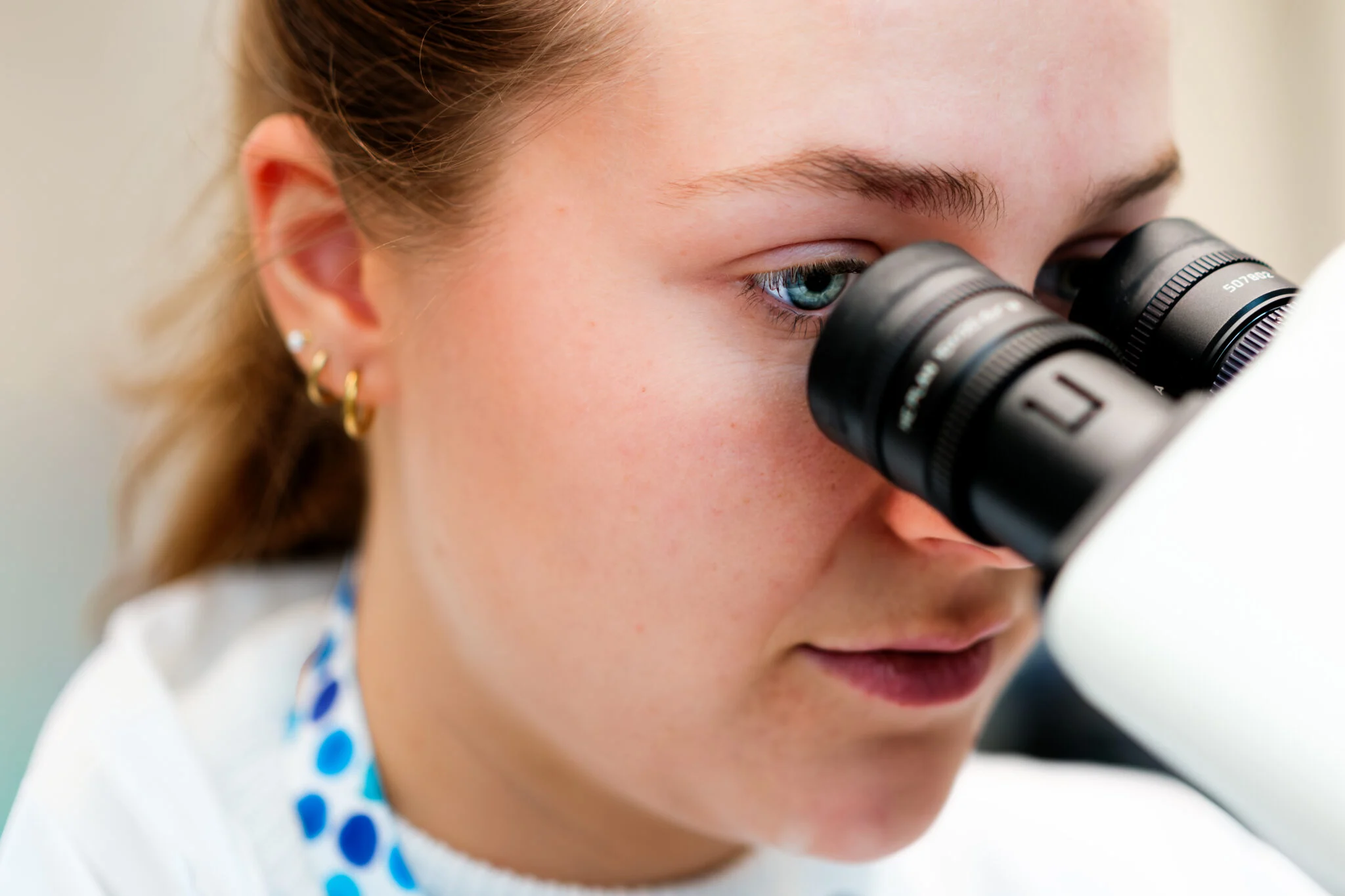 Cerba Research scientist looking through a microscope