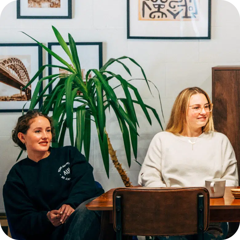 Two smiling women sitting together in a relaxed office