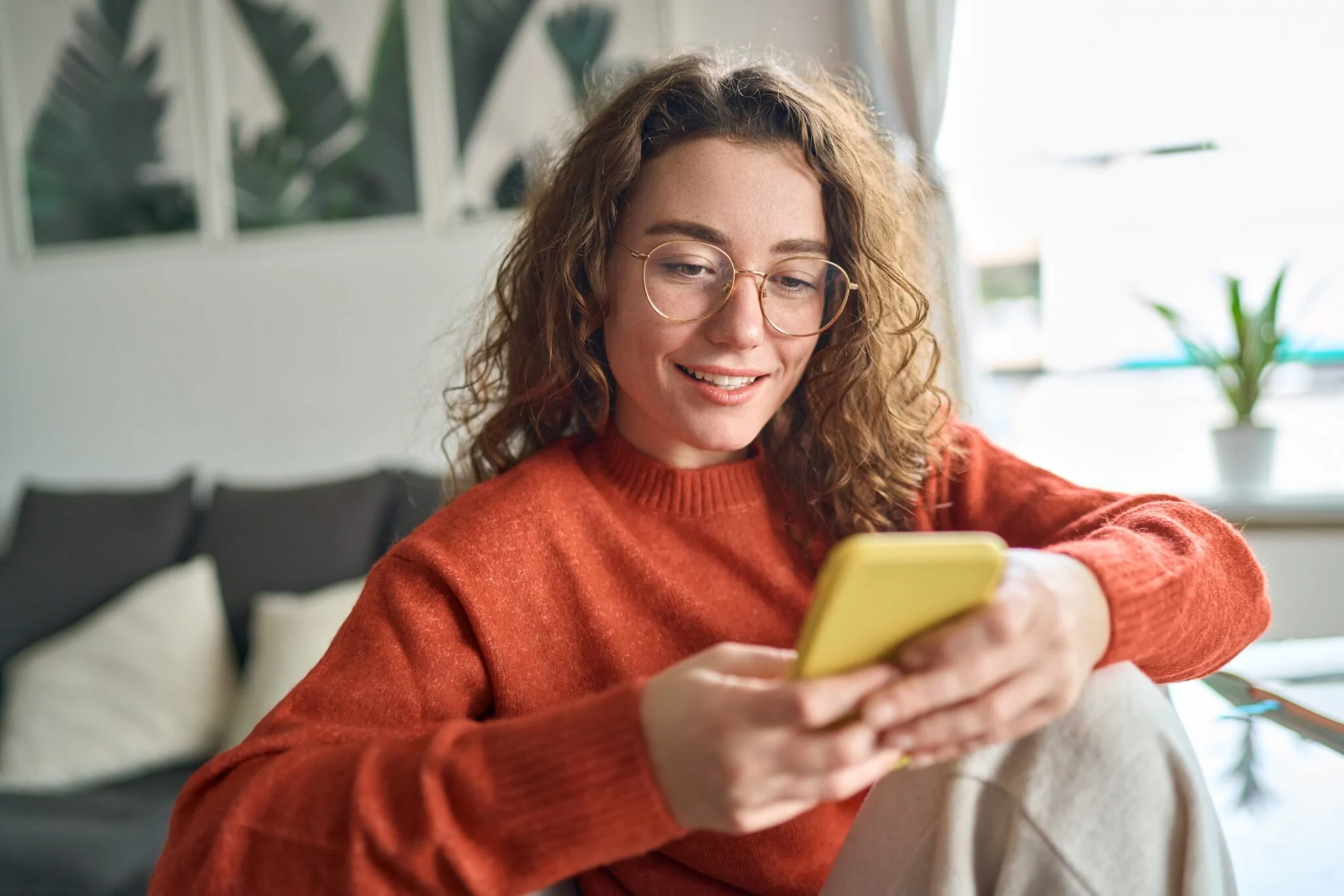 Smiling woman using her phone at home