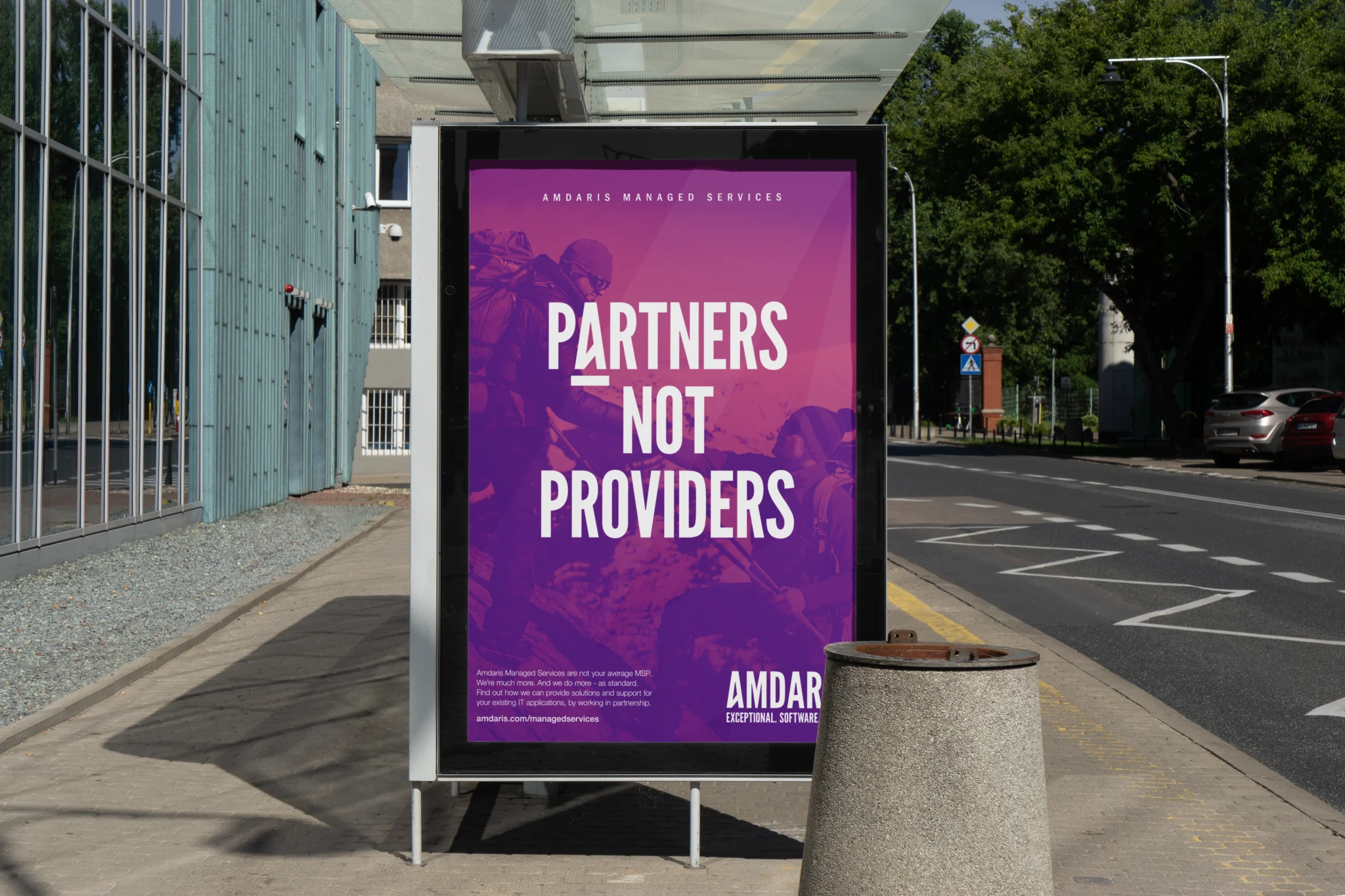 Amdaris "Partners not providers" poster at a roadside bus shelter
