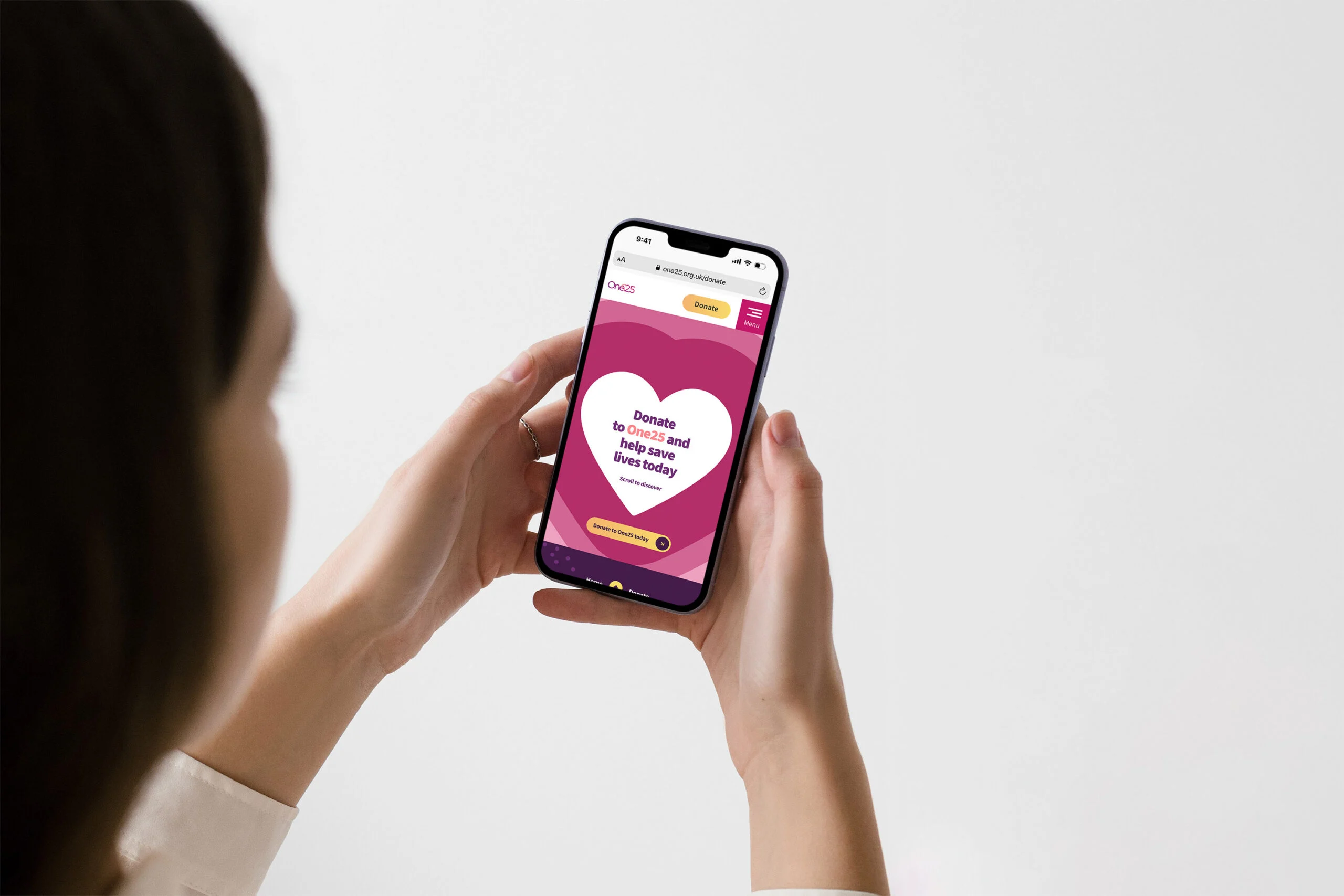 Hand holding a smartphone showing the One25 website