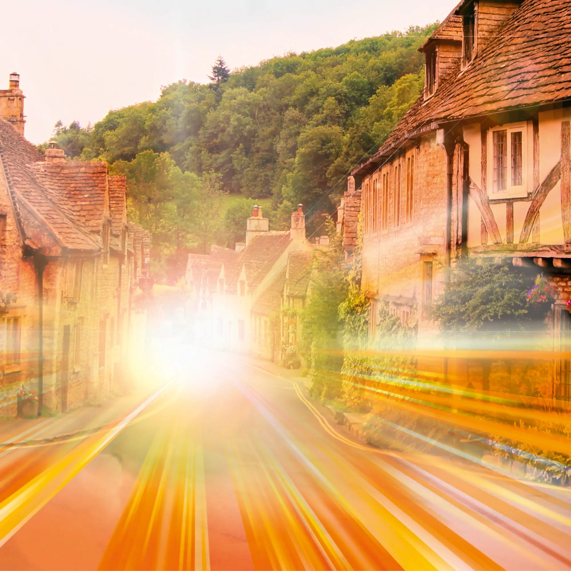 Cotswold village street with golden light trails at sunset