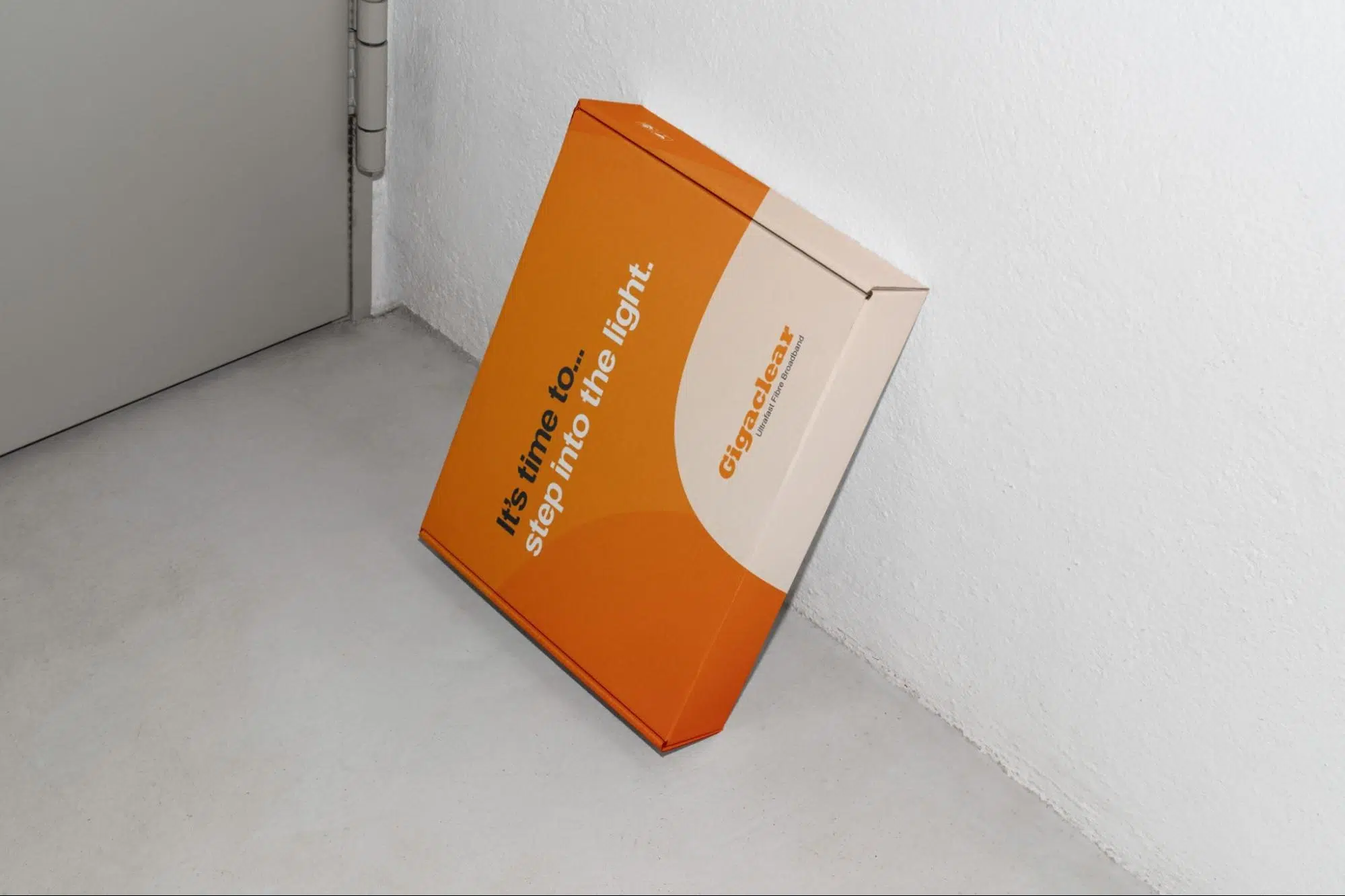 Orange branded delivery box leaning in a white room corner