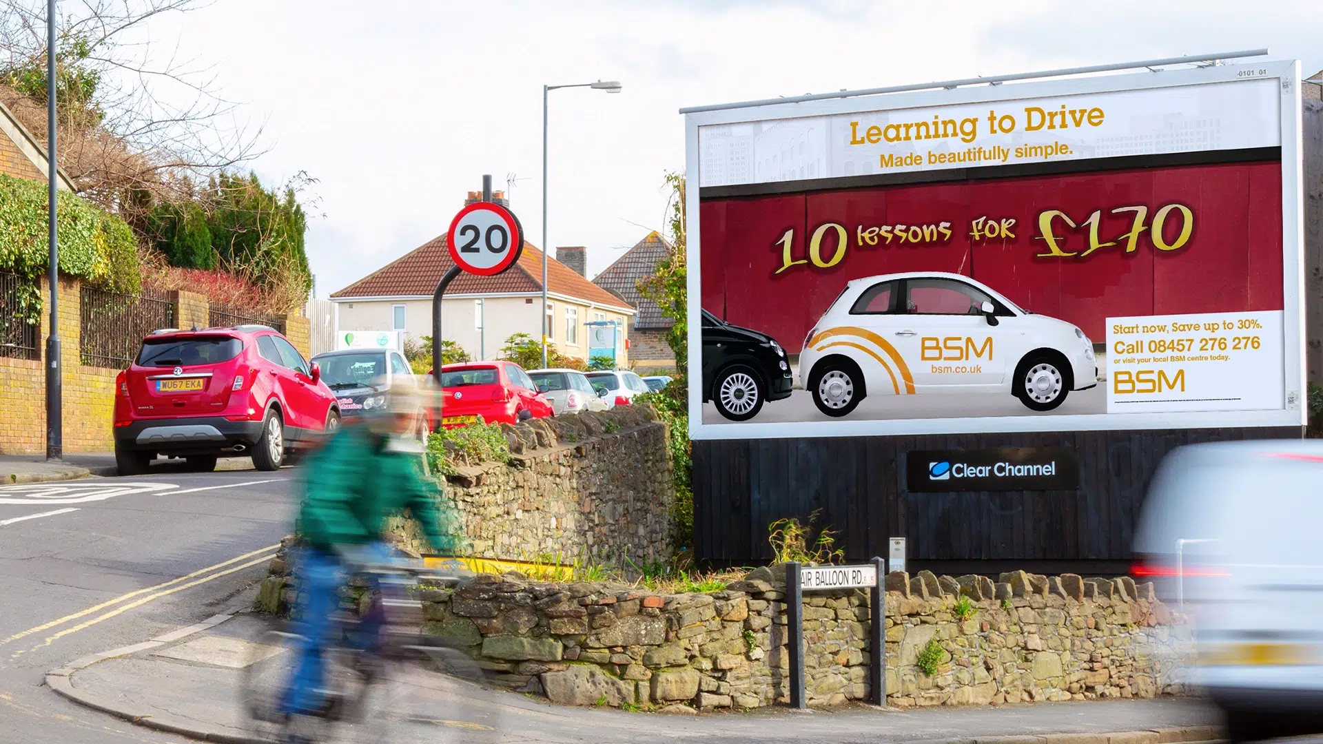 BSM driving lessons billboard beside a busy residential street