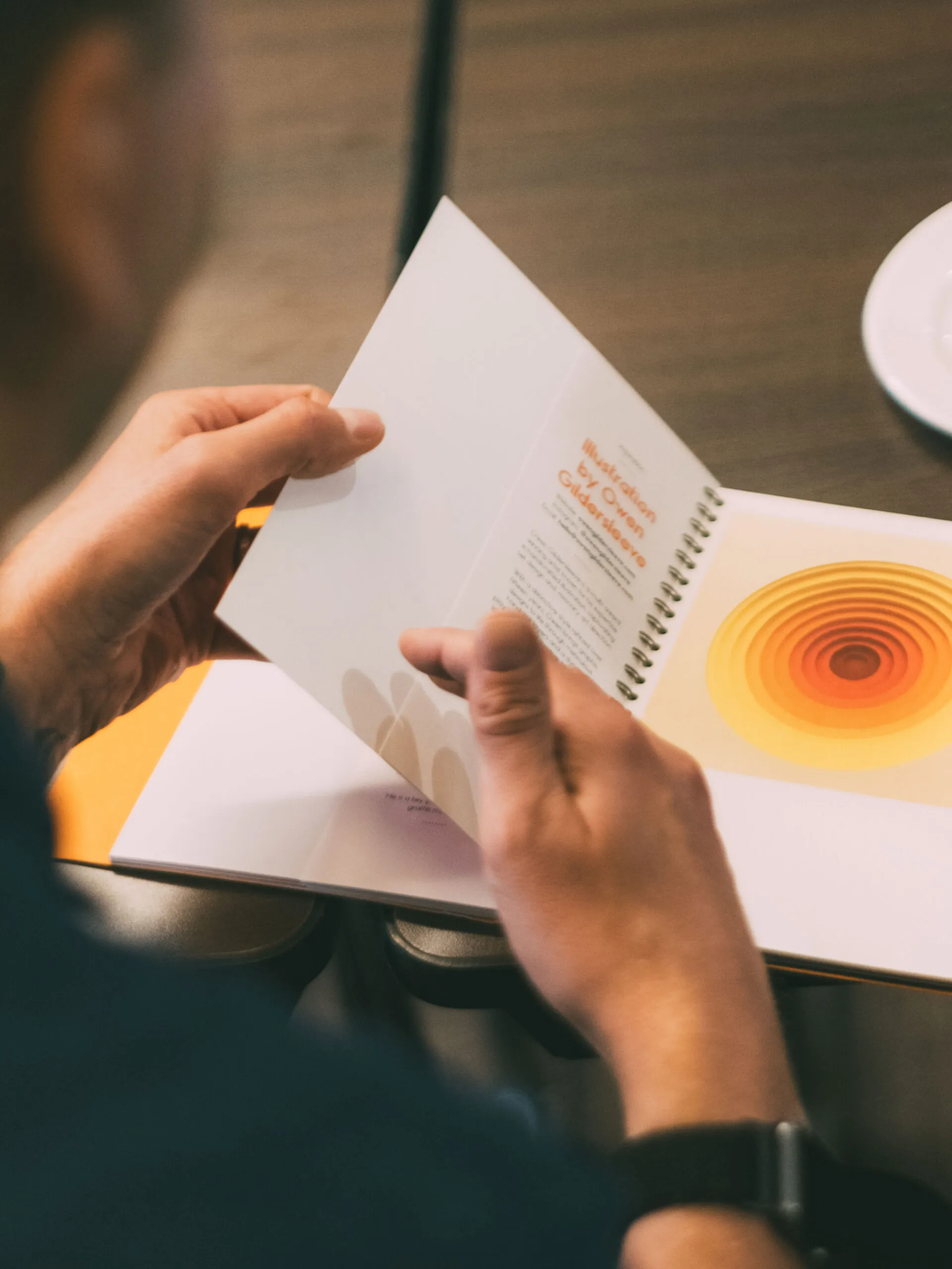 Person reading a booklet with orange circular graphics
