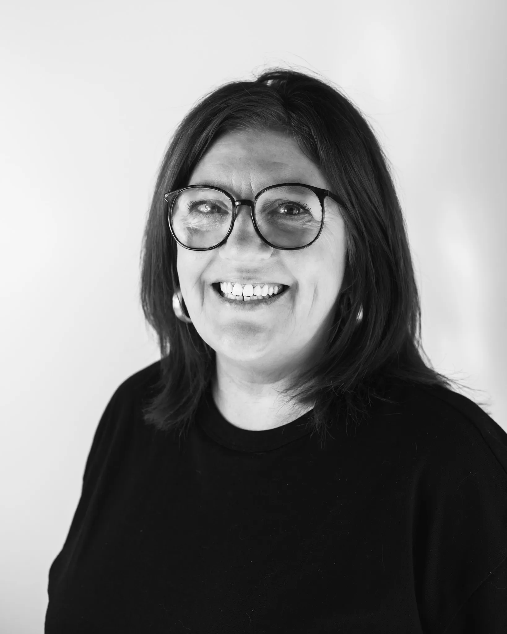 Black and white portrait of a smiling AgencyUK team member in glasses